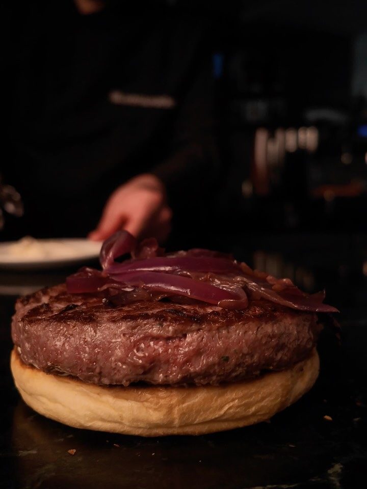 Hamburguesa Ultimate Cheat con cebolla morada sobre fondo negro